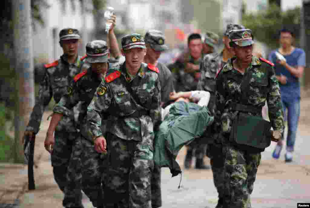 Cảnh sát bán quân sự Trung Quốc khiêng người bị thương trong vụ động đất tại thị trấn Long Đầu Sơn của huyện Lư Điền, tỉnh Vân Nam. 