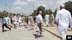 Iraqis gather at the scene of a bomb attack in Baqouba, northeast of Baghdad, Iraq, Friday, May 17, 2013. A bomb killed dozens of people at a Sunni mosque in central Iraq, hitting worshippers as they were emerging from Friday prayers, security officials s
