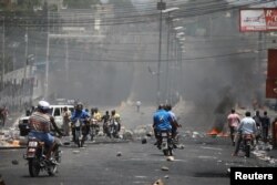 Haitianos atraviesan una barricada en una calle de Puerto Príncipe, Haití, el 8 de julio de 2018. Reuters.