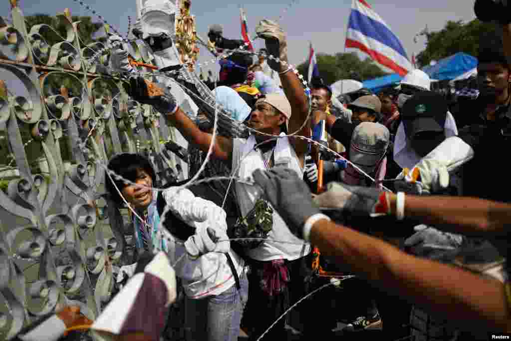 Para demonstran anti pemerintah memotong kawat berduri, sementara sebagian kecil dari mereka memasuki komplek kantor PM Thailand dan memutuskan aliran listriknya, di Bangkok, Kamis (12/12).