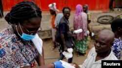 Uma voluntária distribui comida e água a sem-abrigo em Accra, Gana, durante o confinamento obrigatório, devido ao coronavírus