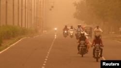 FILE - Commuters make their way amidst haze and dust in Chandigarh, India, June 15, 2018.