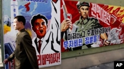 A North Korean man walks past propaganda posters in Pyongyang, North Korea, that threatens punishment to the "U.S. imperialists and their allies," March 26, 2013.