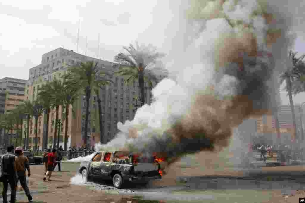 Warga Mesir berusaha memadamkan mobil polisi yang dibakar oleh demonstran yang marah di lapangan Tahrir di ibukota Kairo. Mesir terus dilanda gelombang protes, bentrokan dan kerusuhan antara kelompok pro dan anti pemerintah.