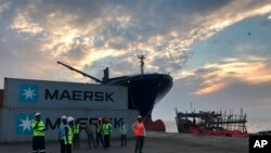Des employé se tiennent devant des conteneurs d'expédition au port de Berbera, à Berbera, Somaliland, Somalie, le 1 avril 2018.
