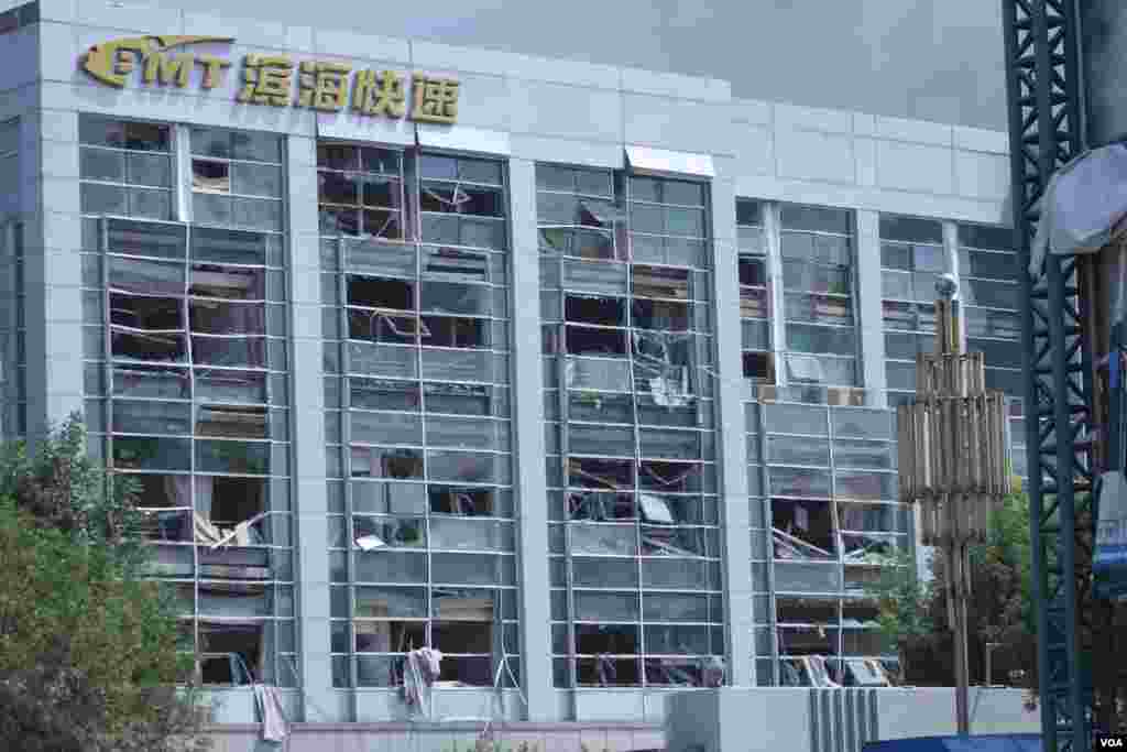 天津爆炸事故現場,核心爆炸區週圍多座居民樓窗戶被震碎,高速公路橋樑受損,多輛大貨車被炸翻,小汽車起火或被砸,多名當地居民仍逗留在事故現場。(美國之音記者東方拍攝)