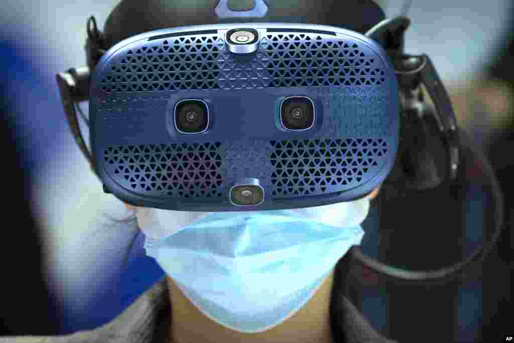 A woman wears a virtual reality headset as she takes a simulated bobsleigh ride at a booth for Chinese telecom provider China Unicom at the PT Expo in Beijing.