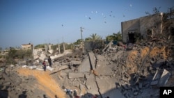 Palestinians sit amid the rubble of their destroyed house following overnight Israeli missile strikes, in the town of Khan Younis, southern Gaza Strip, Nov. 14, 2019.