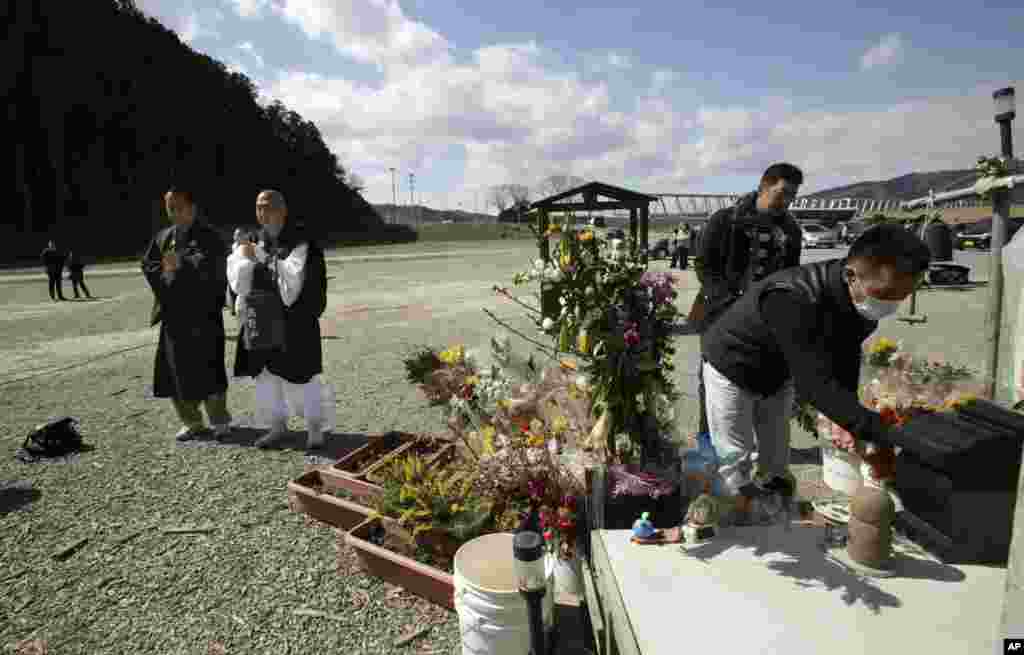 Para biksu melantunkan doa di depan pintu masuk Sekolah Dasar Okawa di Ishinomaki, prefektur Miyagi, tempat 74 dari 108 siswa hilang setelah tsunami menerjang pada 11 Maret 2011. (AP/Shizuo Kambayashi)