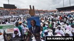 Un homme tient une pancarte représentant l'ancien président ivoirien Laurent Gbagbo lors d'un rassemblement contre la candidature à un 3e mandat du président Ouattara, le 10 octobre 2020 au stade Félix Houphouët-Boigny d'Abidjan.