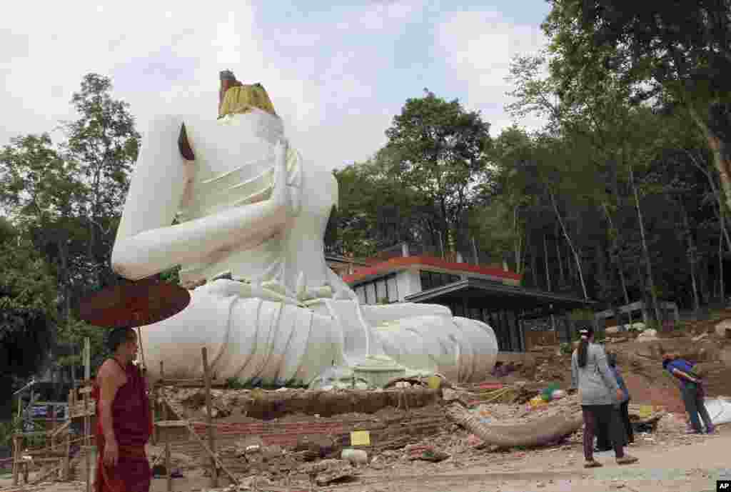Seorang pendeta Budha dan warga memeriksa patung Buddha yang rusak akibat gempa bumi di kuil Udomwaree di Chiang Rai, Thailand utara. 