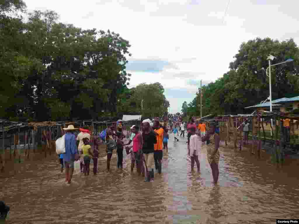 Moun ki kanpe nan yon lari ki anvayi ak dlo ki konn sevi kom yon mache nan tan nomal, nan Wanament, depatman nodes peyi Dayiti, 8 septanm 2017. 