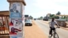 A man rides past a pillar featuring posters of the ruling party presidential candidate, incumbent President John Mahama, and opposition candidate Nana Akufo-Addo in Accra, Oct. 23, 2012.