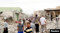 Residents stand amid rubble at blast scene in Tuz Khormato town in northern Iraq, May 21, 2013.