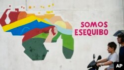 Un niño conduce una motocicleta por delante de un mural con el mapa de Venezuela, que incluye el territorio de Esequibo, en el vecindario 23 de Enero de Caracas, Venezuela, el 11 de diciembre de 2023.