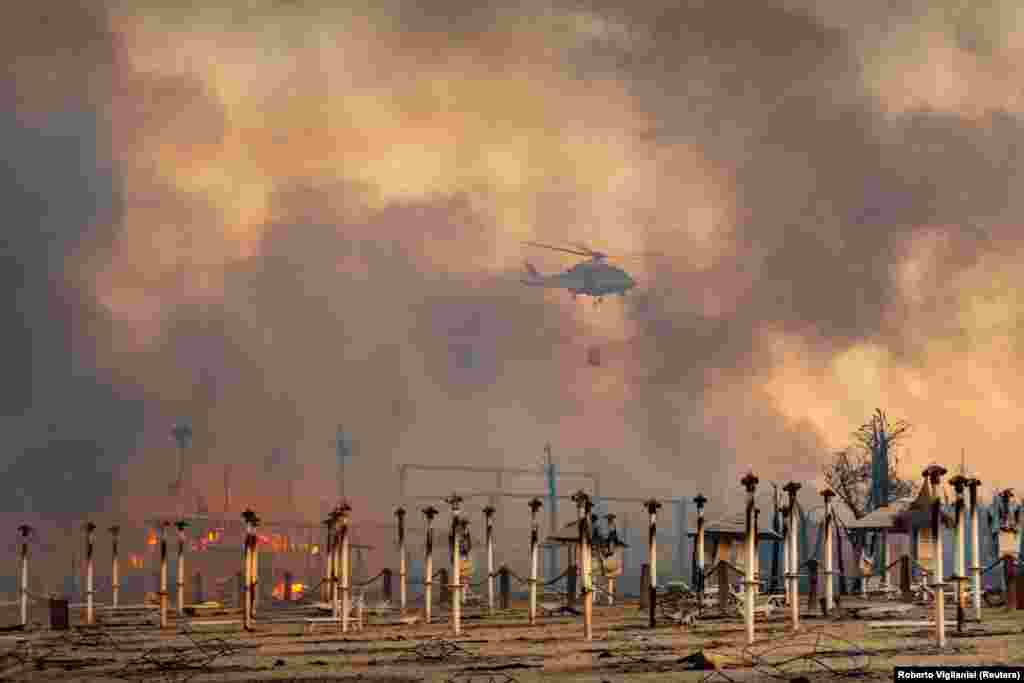A helicopter flies above a fire at Le Capannine beach in Catania, Sicily, Italy, July 30, 2021, in this photo obtained from social media on July 31.