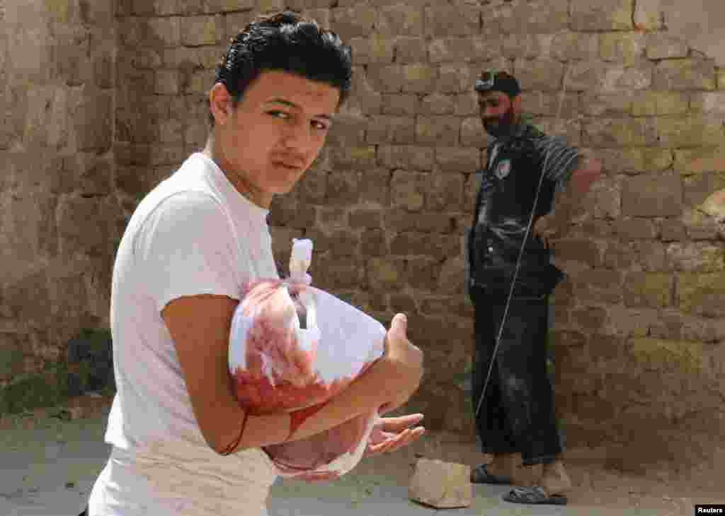 A man carries the body of a dead child after an airstrike in the rebel held Bab al-Nairab neighborhood of Aleppo, Syria.