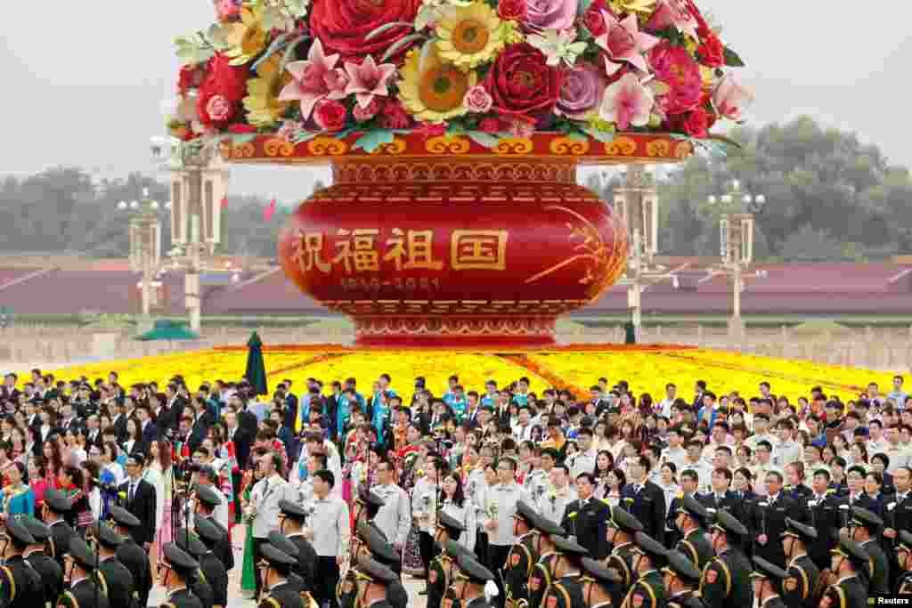 Participants stand in front of a giant flower basket arrangement set up ahead of the Chinese National Day, before a ceremony at the Monument to the People's Heroes on Tiananmen Square to mark Martyrs' Day, in Beijing, China.