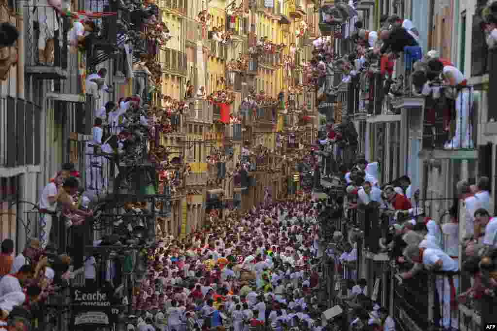 People standing on balconies look at participants as they run in front of Alcurrucen's bulls during the first bull run of the San Fermin Festival in Pamplona, northern Spain, July 7, 2013.