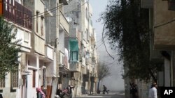 People run for cover from smoke after a shelling in the Karm al-Zeitoun area in Homs, Syria, March 12, 2012. (Reuters)