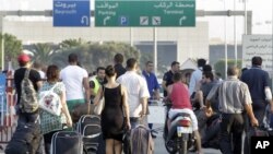 Travelers carry their luggage, as they walk towards the Beirut Rafik Hariri international airport after some of the families of 11 Lebanese pilgrims kidnapped in Syria blocked the highway leading to Beirut airport to protest the Lebanese government's fail