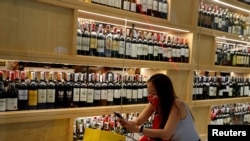 FILE - A woman wearing a protective mask lines up outside a liquor shop after Bangkok and several other provinces announced a 10-day ban on alcohol sale starting April 10 during the coronavirus disease outbreak in Bangkok, Thailand, April 9, 2020.