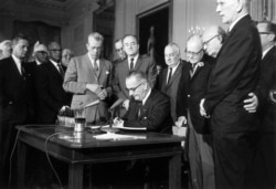 FILE - President Lyndon Johnson signs the Civil Rights Act in the East Room of the White House, July 2, 1964.