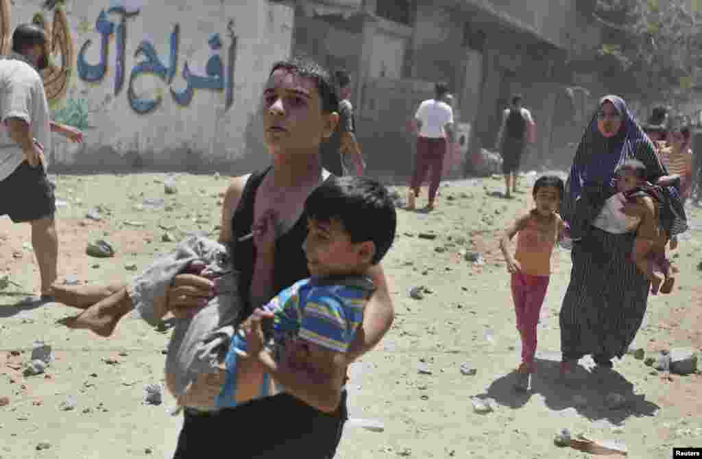 Palestinians run following what police said was an Israeli air strike on a house in Gaza City, July 9, 2014.