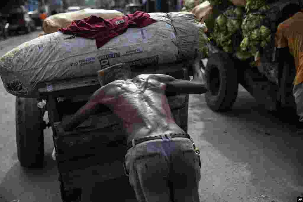 A porter pushes a loaded cart from the Croix de Bossales food market and makes his way through downtown Port-au-Prince, Haiti, Oct. 4, 2021.