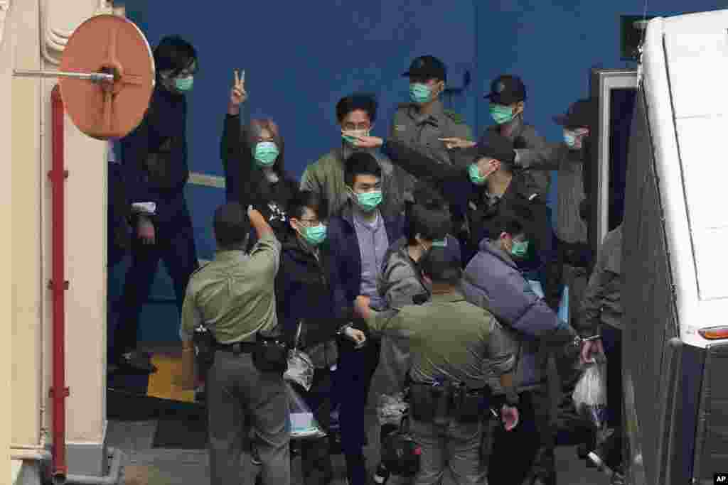 Former lawmaker Leung Kwok-hung, known as "Long Hair," second left, shows a victory sign as some of the 47 pro-democracy activists are escorted by Correctional Services officers to a prison van in Hong Kong.