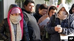 Inmigrantes indocumentados desafían el frío haciendo linea para obtener su licencia de conducir de California, en Stanton, California.
