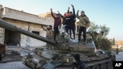 Para pejuang pro-Turki di Suriah berpose di atas sebuah tank di Maarat al-Numan, wilayah barat daya Aleppo, Suriah (30/11). 