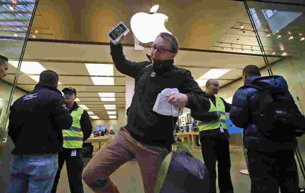 Seorang pembeli berjingkrak girang dengan iPhone 5S baru di tangan saat meninggalkan toko Apple di Oberhausen ketika penjualan iPhone baru dimulai di Oberhausen, Jerman.