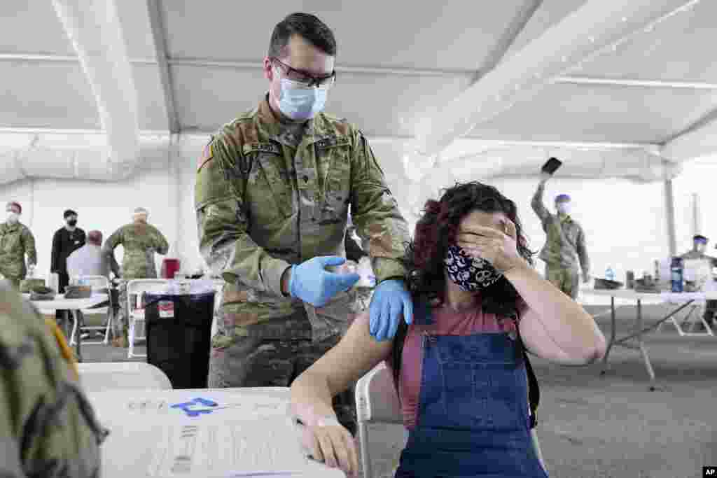 Leanne Montenegro covers her eyes while she receives the Pfizer COVID-19 vaccine at a FEMA vaccination center at Miami Dade College, April 5, 2021, in Miami, Florida.