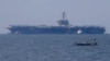 一艘小渔船从停靠在菲律宾马尼拉的美国海军卡尔文森号航空母舰附近驶过。（2018年2月17日