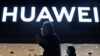 FILE - Residents pass by a Huawei electronics store in Beijing, April 12, 2021. 