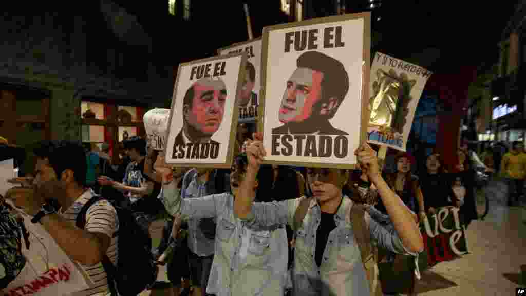 Para demonstran memegang poster-poster Presiden Meksiko Enrique Pena Nieto (kanan) dan Jaksa Agung Jesus Murillo Karam (kiri) dalam protes atas hilangnya 43 mahasiswa di negara bagian Guerrero, di Mexico City (5/11). (AP/Eduardo Verdugo)
