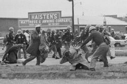 FILE - A state trooper swings a billy club at John Lewis, right foreground, chairman of the Student Nonviolent Coordinating Committee, to break up a civil rights voting march in Selma, Ala., March 7, 1965.