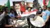 Palestinians carry trays of sweets and an Egyptian flag (C) in front of a placard depicting Egypt's Muslim Brotherhood's presidential candidate Mohamed Morsi in Gaza City, June 18, 2012.