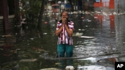 A woman reacts while wading in floodwater in Jakarta, Indonesia, Jan. 4, 2020. Monsoon rains and rising rivers submerged parts of greater Jakarta and caused landslides in Bogor and Depok districts on the city's outskirts as well as in neighboring Lebak.