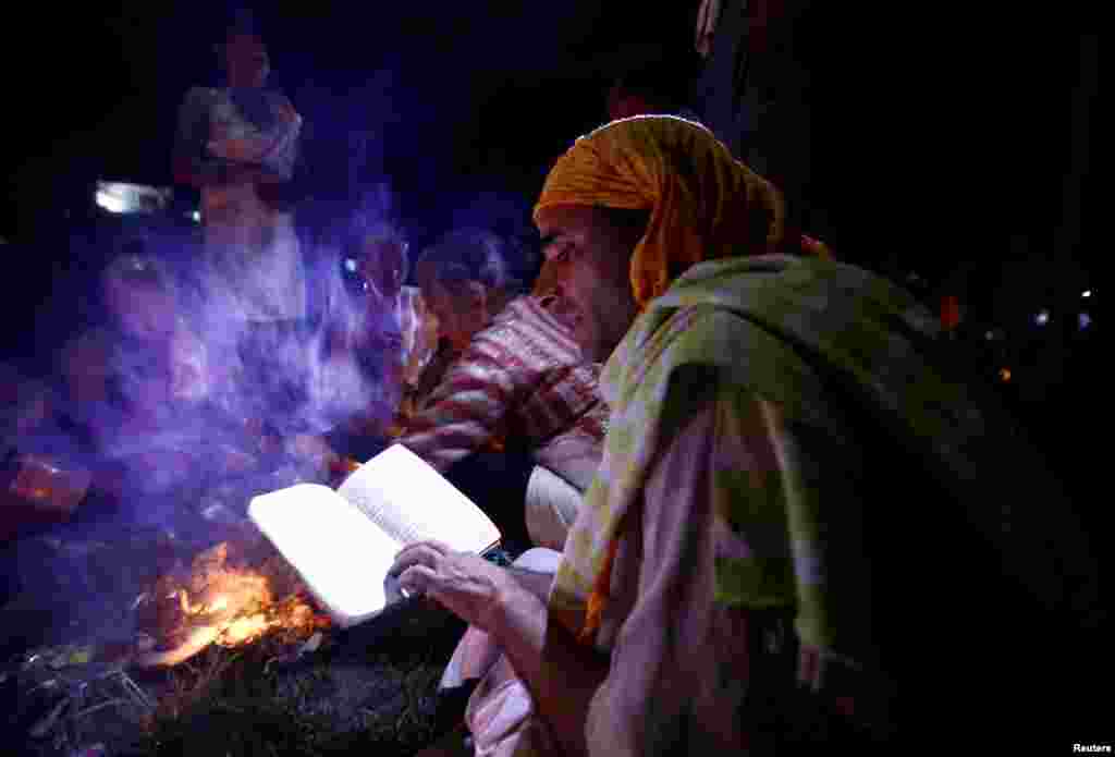 A Hindu priest recites prayers from a holy book while performing a ritual near the bank of Bagmati River during Kuse Aunse (Father's Day) at Gokarna Temple in Kathmandu, Nepal.