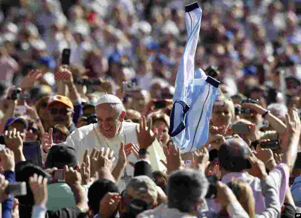 A faithful tosses in the air a jersey with the colors of the Argentine flag as Pope Francis greets faithful upon arrival for his weekly general audience in St. Peter's Square at the Vatican.