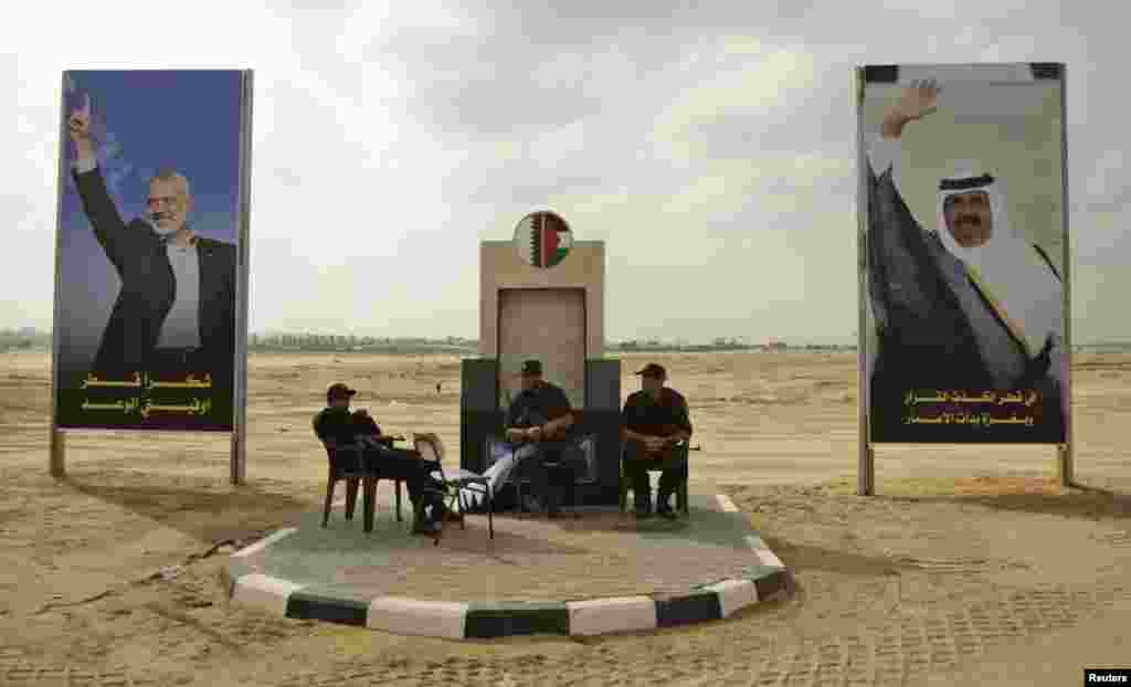 Thành viên lực lượng an ninh Hamas ngồi giữa những tấm poster ảnh thủ tướng Hamas Ismail Haniyeh (trái) và quốc vương Qatar Hamad bin Khalifa al-Thani ở Khan Younis, phía nam Dải Gaza, 22 tháng 10, 2012.