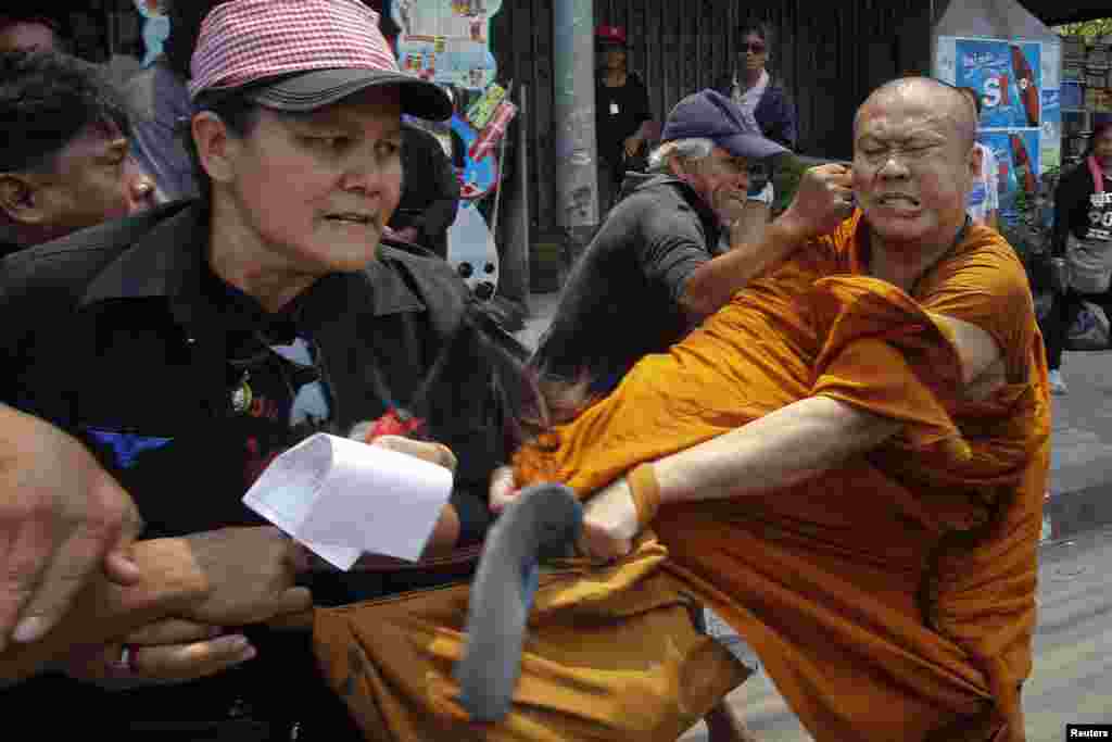 Members of the pro-government "red shirt" movement attack a Buddhist monk outside the National Anti-Corruption Commission office in Nonthaburi province, on the outskirts of Bangkok, Thailand.
