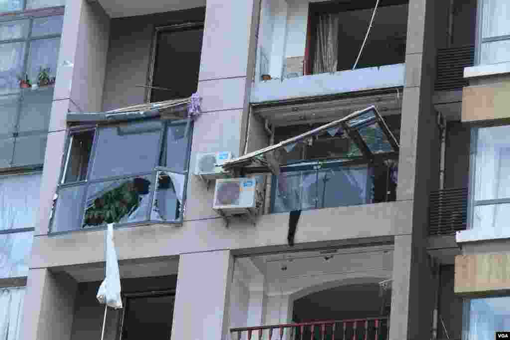 天津爆炸事故現場,核心爆炸區週圍多座居民樓窗戶被震碎,高速公路橋樑受損,多輛大貨車被炸翻,小汽車起火或被砸,多名當地居民仍逗留在事故現場。(美國之音記者東方拍攝)