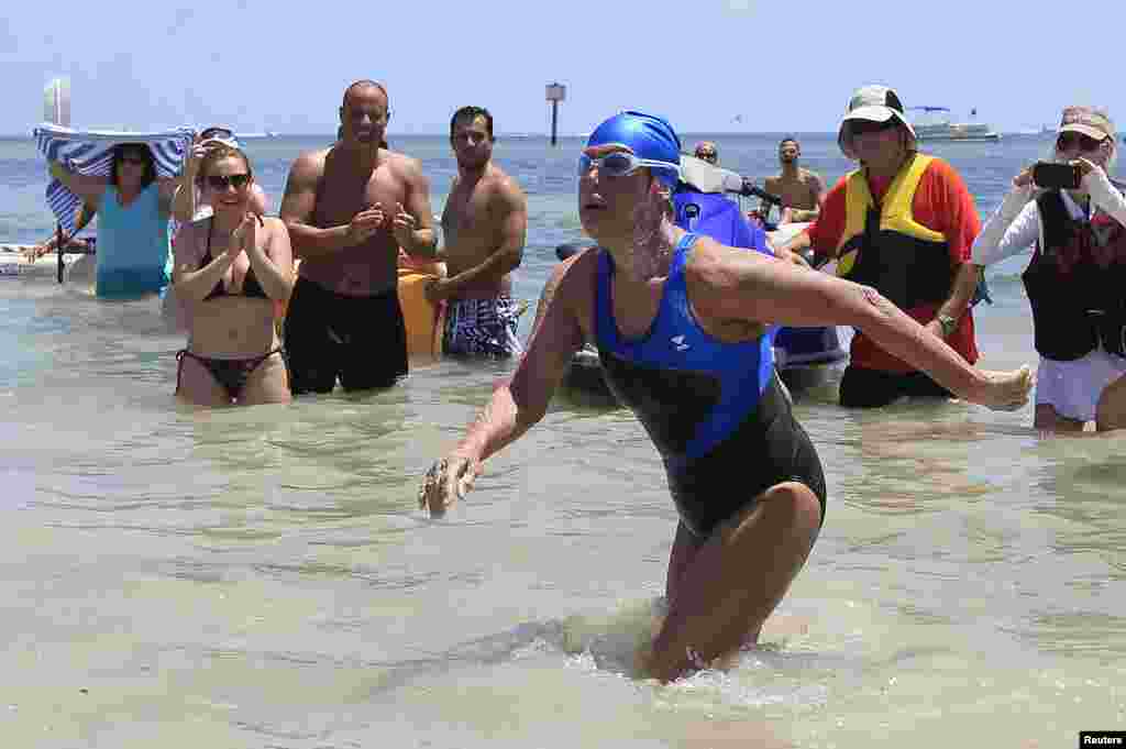 Perenang jarak jauh puteri AS Diana Nyad, 64 tahun (baju renang biru), setelah menyelesaikan berenang dari Kuba ke Key West, Florida dalam waktu sekitar 53 jam.