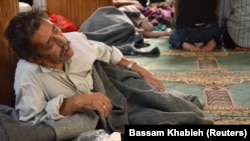 FILE - A survivor from what activists say is a gas attack rests inside a mosque in the Duma neighborhood of Damascus, August 21, 2013. 