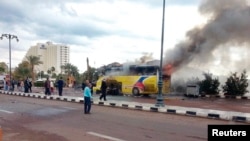 Security officials and onlookers are seen at the site of a tourist bus blast in the Egyptian south Sinai resort town of Taba, Feb. 16, 2014.