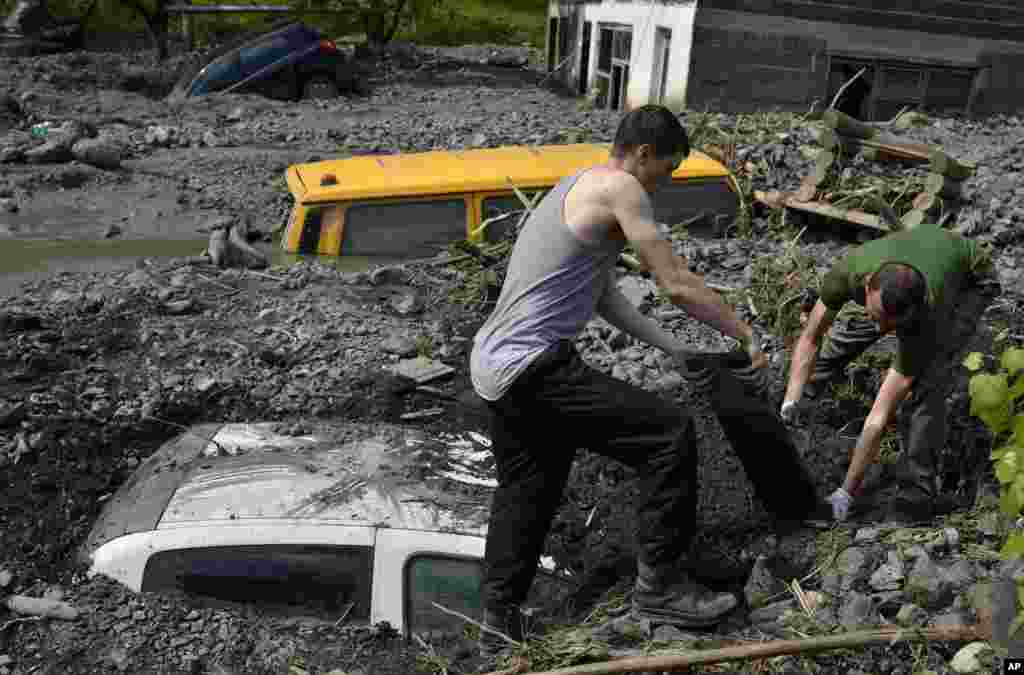 Residents try to excavate a car trapped in the mud caused by a landslide at the village of Topcic Polje, near Zenica, Bosnia-Herzegovina, May 20, 2014.