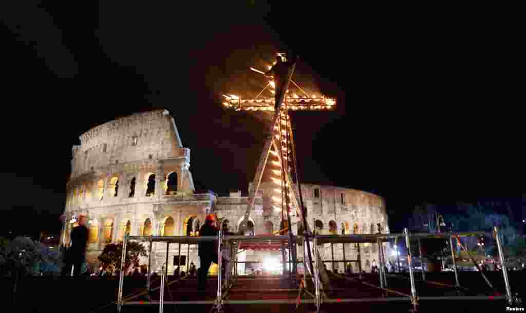 Seorang pekerja menyalakan salib sebelum Paus Fransiskus I memimpin prosesi Via Crucis (Jalan Salib) dalam perayaan Jumat Agung di depan Koloseum di Roma (29/3). (Reuters/Alessandro Bianchi)